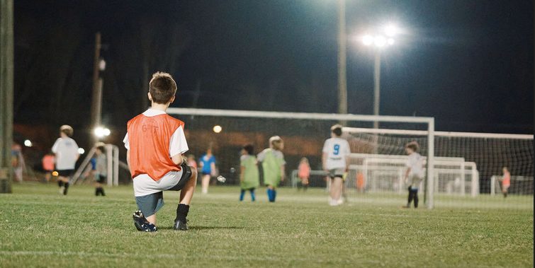 JFC Older Recreational player kneeling on the field under the lights