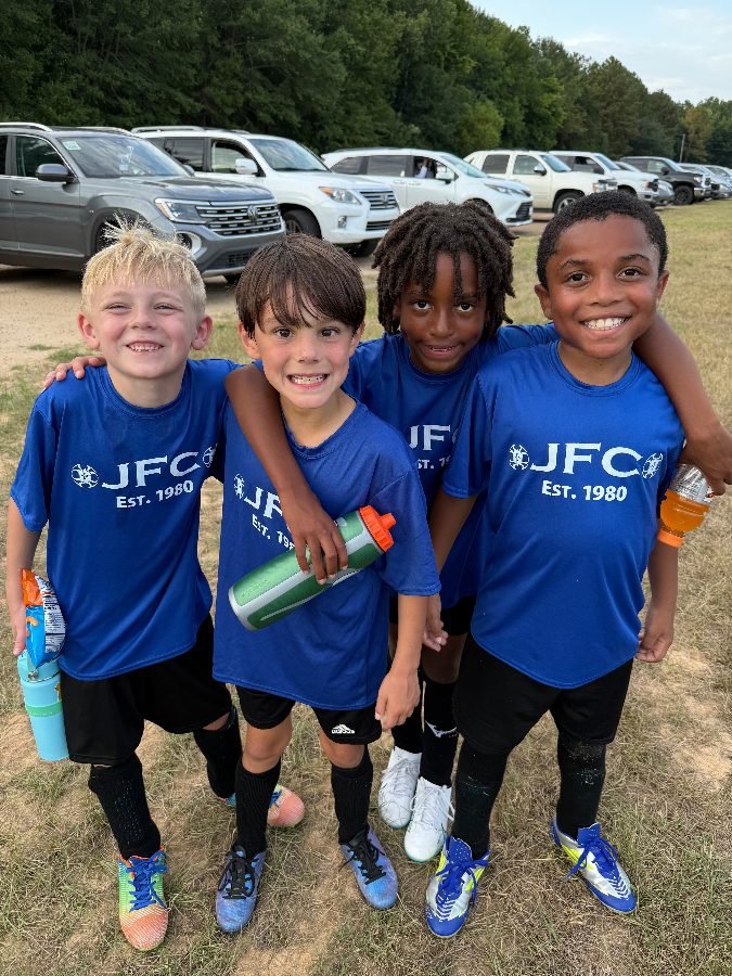 Four young JFC players in blue kit after a recreational game
